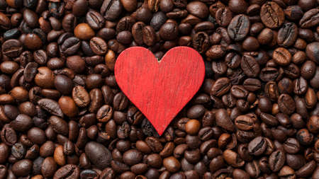 Red wooden heart resting on a bed of fresh roasted coffee beansの写真素材