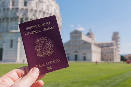 Man hold an italian passport in front of the world famous leaning tower of Pisaの写真素材