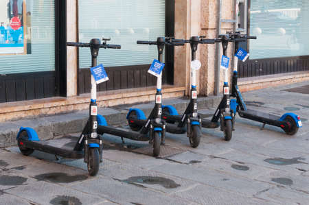 Pisa, Italy - June 23, 2021 - Row of electric scooters parked waiting to be rentedのeditorial素材