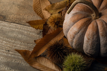 Autumn background: pumpkin on chestnut leaves on a wooden table