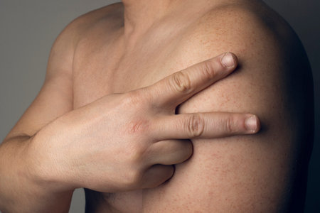 Man makes a V with his fingers on his arm to indicate that he is vaccinatedの写真素材