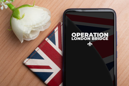 Operation London Bridge concept: a smartphone over a wallet and a rose on a wooden table. The operation London Bridge ia s plan for what will happen after Queen death.の写真素材