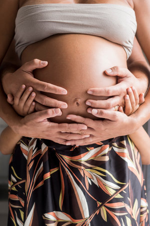 Family hold hands on the belly of the pregnant motherの写真素材