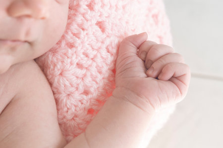 Detail of the hand of a baby girl wrapped in a pink wool blanketの写真素材