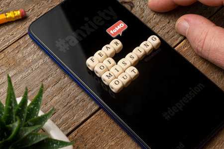 Fear of missing out (fomo) concept: smartphone on a wooden table with some die composing a sentence.の写真素材