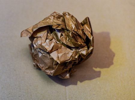 Crumpled paper ball on brown background. Recycling concept