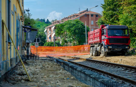 railway construction yard with truck, barrier and old stationの写真素材