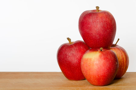 pile of red apples on a chopping board with white backgroundの写真素材