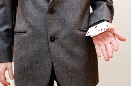 Businessman holding a poker of aces card in his hands, hidden in his sleeveの写真素材