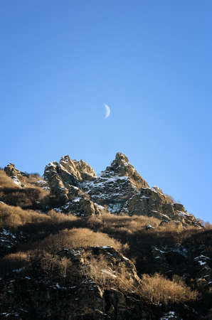 mountain peaks of italian Alps with rising moon at late afternoonの写真素材