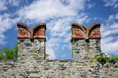 Castle wall merlons on a fortified wall in Italy with swallowtail shape and clouds on the backgroundの写真素材