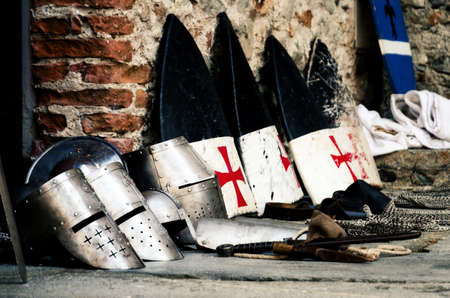 Medieval weapons, shields and helmets from the crusade age on a castle floor during an historical reenactmentの写真素材