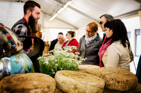 BRA, ITALY - SEPTEMBER 18, 2017: traditional hard cheese on a market stall in Bra (Italy), on september 18, 2017, with cheesemaker and customersのeditorial素材
