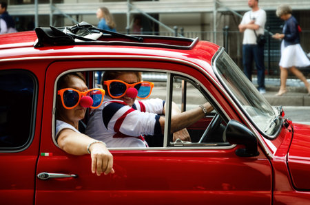 TURIN, ITALY - SEPTEMBER 24, 2017 - Funny looking couple driving an old red Fiat 500 during a...