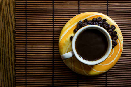 yellow and orange coffee cup with saucer seen from aboveの写真素材