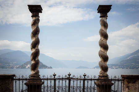 Varenna, Italy - July 28,2018: Cloudy misty morning view of the Como Lake from the botanical garden of Villa Monastero in Varenna, italy, on july 28, 2018, with balcony and columnsのeditorial素材
