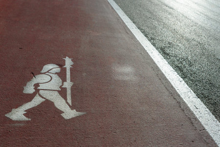 Funny pedestrian sidewalk in the medieval village of Gradara (Italy), with a middle age soldier shape over the white and red stripes on asphalt roadの写真素材