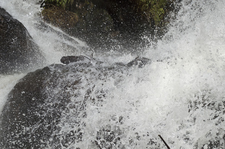 Water flowing roughly by the rocks at a waterfallの写真素材