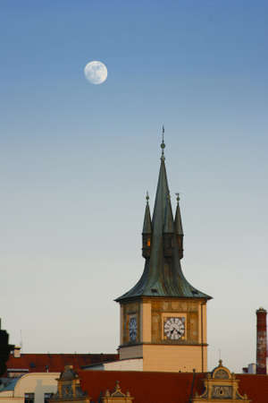 Medieval tower with clock and moon on evening sky in Prague cityの写真素材