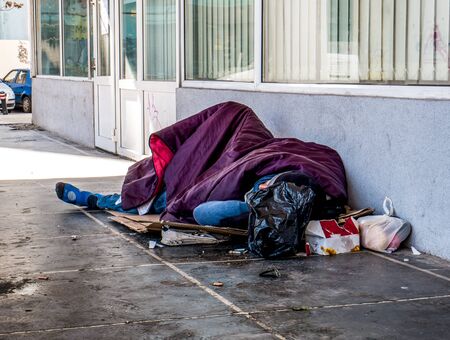 Homeless man sleeping on the street and covered with blanket. Homeless man in Bucharest, Romania.の写真素材