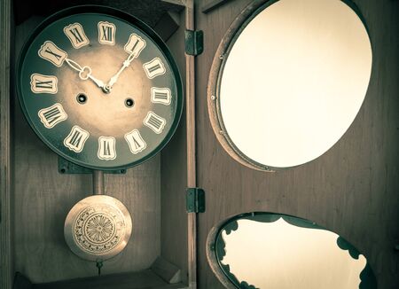 Old vintage wall clock with pendulum. Vintage wall clock made in former Soviet Union (USSR). Old clock pointing time.の写真素材