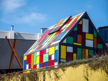 Small house made of colored glass with blue sky in the background.の写真素材
