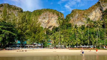 Krabi/Thailand - 02.20.2019: Pai Plong Beach near Ao Nang town in Krabi, Thailand. Tourists on a tropical beach surrounded by limestone formations and palm trees.の写真素材