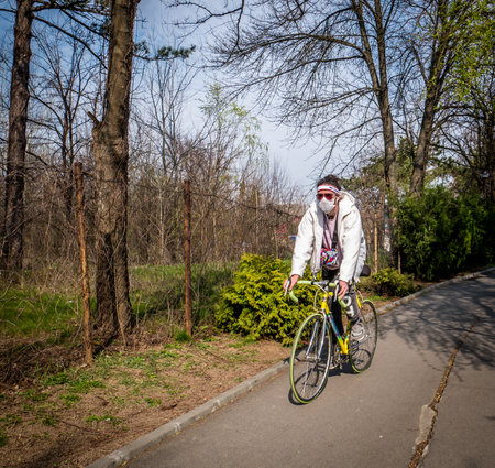 Bucharest/Romania - 03.19.2020: Man ridding a bike wearing a face mask. Coronavirus pandemic protection.のeditorial素材