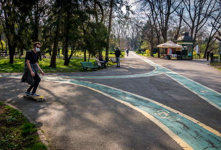 Bucharest/Romania - 03.19.2020: Young man on a skateboard in a park wearing a face mask for protection against Coronavirus pandemic.のeditorial素材
