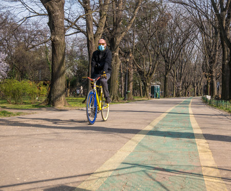 Bucharest/Romania - 03.19.2020: Man ridding a bike wearing a face mask. Coronavirus pandemic protection.のeditorial素材