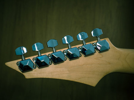 Guitar head with silver tuning pegs or keys. Close up with tuners or machine heads of a guitar.