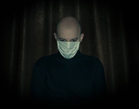 Bald man wearing a face mask in isolation to protect himself against coronavirus. Portrait of a depressed man in isolation.の写真素材