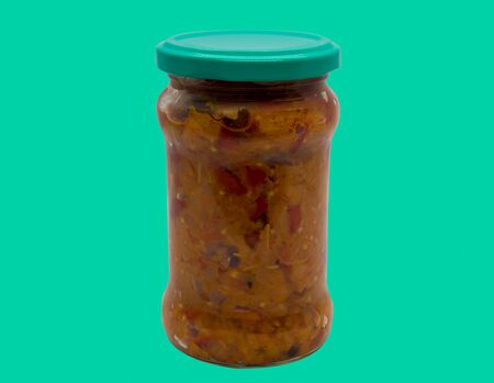 Traditional romanian mash vegetables (zacusca) in a glass jar on a green background.の写真素材
