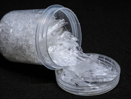 Natural menthol crystals on a black background. small plastic recipient filled with menthol crystals.の写真素材