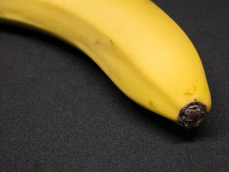 Close up with a single yellow banana on black background.の写真素材