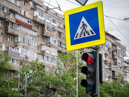 Zebra crossing sign and traffic light in Bucharest, . Red traffic light with worn out apartment buldingfrom communist era in the backgroundの写真素材