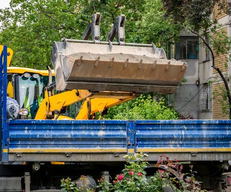 Backhoe loader loading sand or dirt in a vehicle. Construction equipment.の写真素材