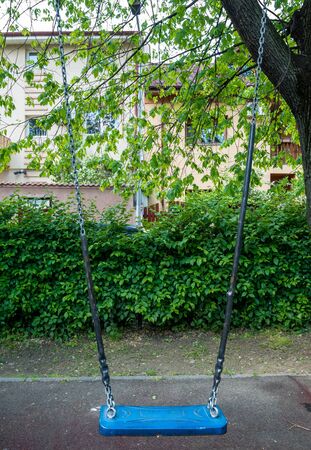 A children's playground in Bucharest, Romania. Children swings in a park with trees.の写真素材