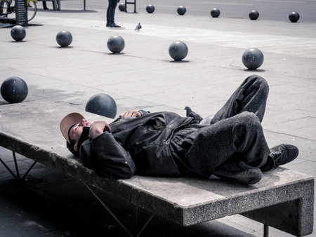Bucharest/Romania - 05.07.2020: Homeless man sleeping on a bench in the middle of the day , in Bucharest, Romania.のeditorial素材