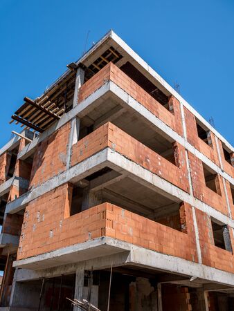 Apartment buliding under construction. Unfinished construction bulding against blue sky.の写真素材