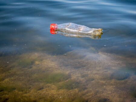 A PET plastic bottle floating on water of a lake in Bucharest, Romania. Plastic pollution environment concept.の写真素材