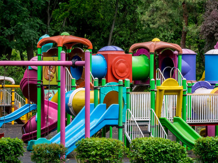An empty children's playground in Bucharest, Romania. Children swings and slides in a park with trees.の写真素材