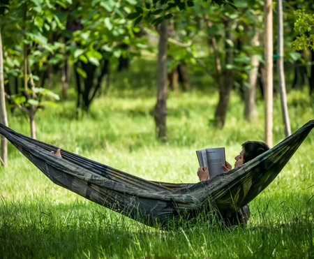 Bucharest/Romania - 05.16.2020: Girls relaxing in a hammock and reading a book.のeditorial素材