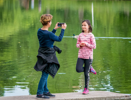 Bucharest/Romania - 05.23.2020: Mother taking a picture to her doughter with smartphone, in the Youth Park, Bucharest.のeditorial素材