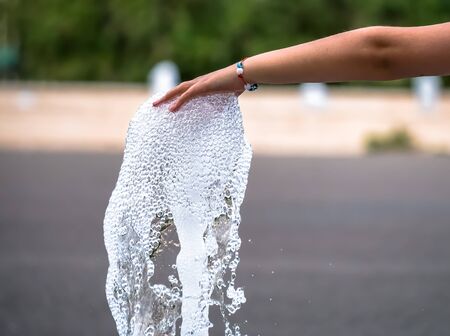 Girl's hand playing with a stream of water from a fountain.の写真素材