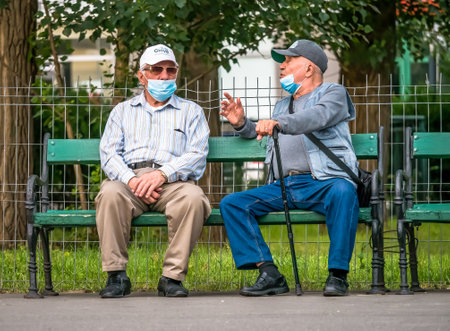 Bucharest/Romania - 05.23.2020: Two old man sitting on a bench in the park and talking.のeditorial素材