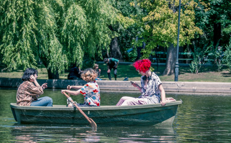 Bucharest/Romania - 05.30.2020: Girl with red hair in a boat, in Cismigiu park looking at her phone. Smart phone addiction concept.のeditorial素材