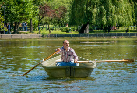 Bucharest/ Romania - 05.30.2020: Man on a boat paddling. Man enjoying a nice summer or spring day in Cismigiu park, Bucharestのeditorial素材