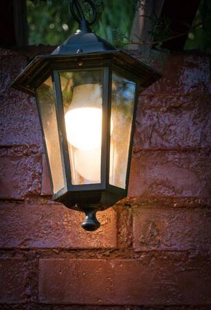 Vintage street lamp or lamp post hanging in front of a red brick wallの写真素材