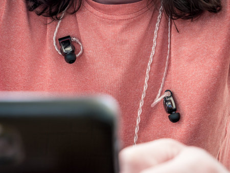 Man wearing intra auricular headphones around his neck. Headphones with professional balanced cable.